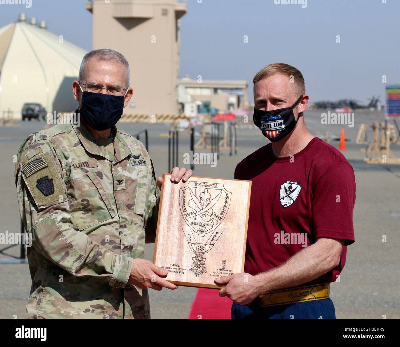 U.S. Army Capt. Sam DeBold, right, support operations officer with Headquarters Support Company, 628th Aviation Support Battalion, 28th Expeditionary Combat Aviation Brigade, receives a handmade plaque from Col. Howard Lloyd, 28th ECAB commander, for being the top finisher in the Task Force Anvil Marathon. About 120 Soldiers raced in memory of Michael J. Novosel, Sr., a native of Etna, Pennsylvania, who served for over 40 years as an Army aviator and received the Medal of Honor for rescuing 29 Soldiers during the Vietnam War. Stock Photo