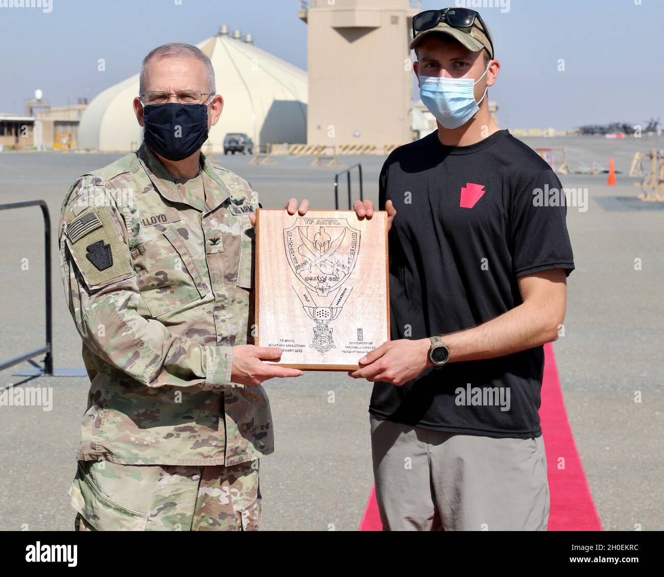 U.S. Army Capt. Matthew Groff, right, a UH-60 pilot with 2-104th General Support Aviation Battalion, 28th Expeditionary Combat Aviation Brigade, receives a handmade plaque from Col. Howard Lloyd, 28th ECAB commander, for being the top finisher in the Task Force Anvil Half-Marathon. About 120 Soldiers raced in memory of Michael J. Novosel, Sr., a native of Etna, Pennsylvania, who served for over 40 years as an Army aviator and received the Medal of Honor for rescuing 29 Soldiers during the Vietnam War. Stock Photo