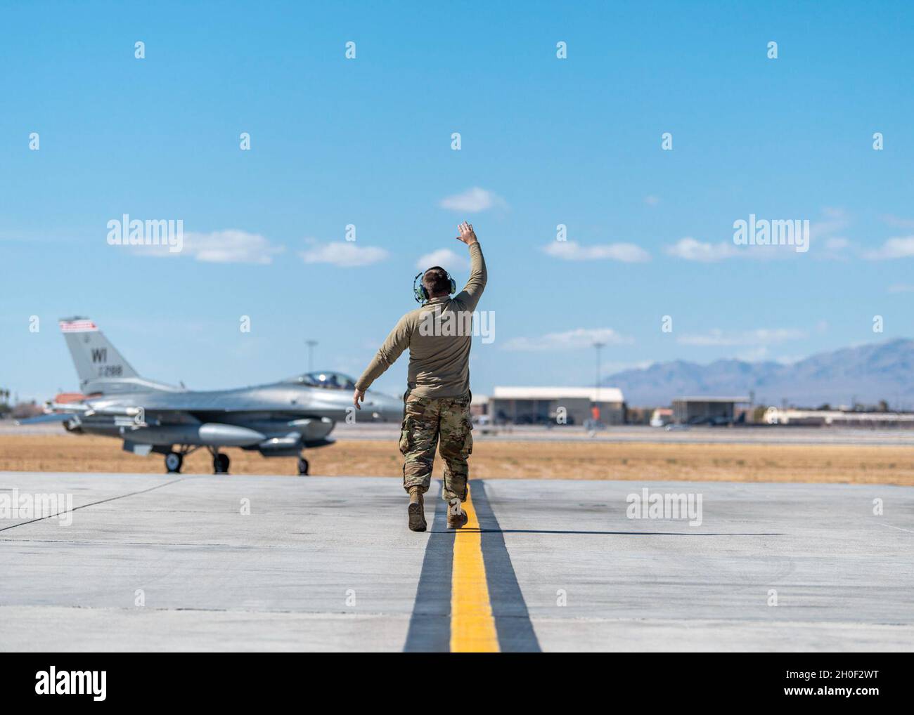 U.S. Air Force Airman 1st Class Mark Raasch, a crew chief assigned to the 115th Fighter Wing, Madison, Wisconsin, marshalls an F-16 Fighting Falcon, assigned to the 176th Fighter Squadron at the 115th FW, at Nellis Air Force Base, Nevada March 17, 2021 during Red Flag 21-2. Red Flag exercises provide mission commanders, maintenance personnel, ground controllers, and air, space and cyber operators the opportunity to experience realistic combat scenarios in preparation for future warfare. Stock Photo