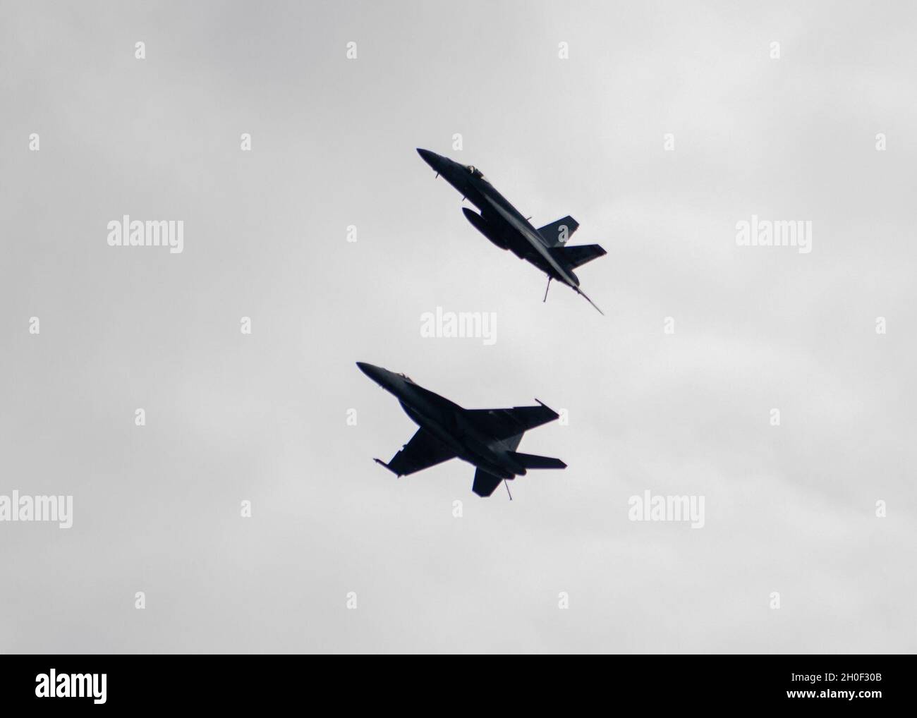 PACIFIC OCEAN (Feb. 20, 2021) - Two F/A-18E Super Hornets, assigned to the “Golden Warriors” of Strike Fighter Squadron (VFA) 87, fly over the aircraft carrier USS Theodore Roosevelt (CVN 71) Feb 20, 2021. The Theodore Roosevelt Carrier Strike Group is on a scheduled deployment to the U.S. 7th Fleet area of operations. As the U.S. Navy’s largest forward-deployed fleet, 7th Fleet routinely operates and interacts with 35 maritime nations while conducting missions to preserve and protect a free and open Indo-Pacific Region. Stock Photo