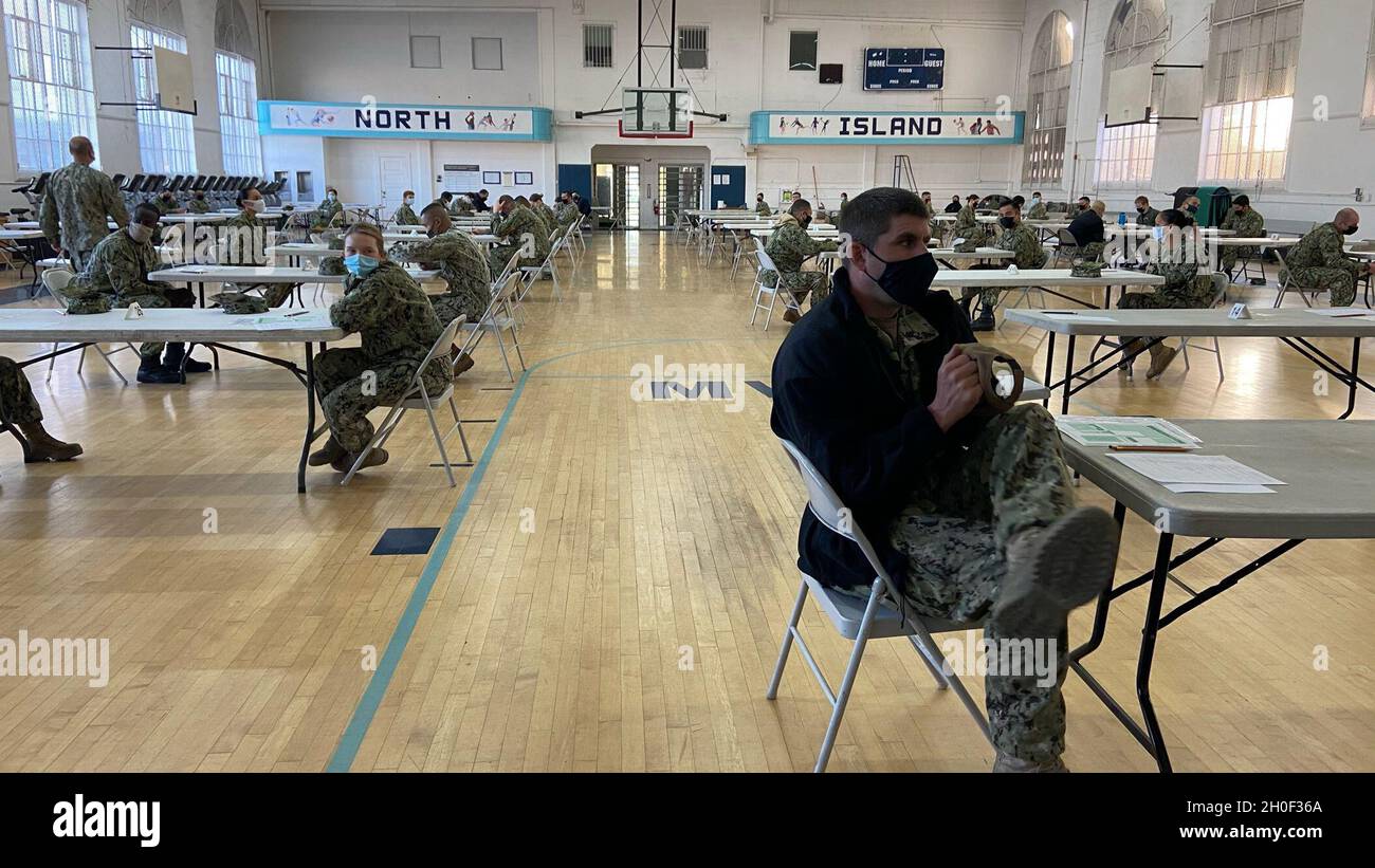 Navy Reserve Sailors sit in a gymnasium prior to the start of the Navy