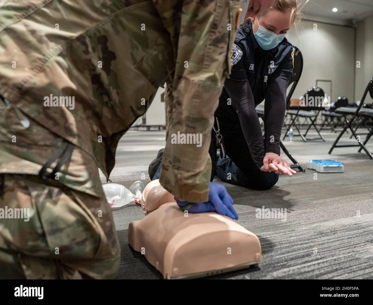 U.S. Army 1st Lt. Jack Stapleton, assigned to A Co. 1st Battalion 69th Infantry Regiment, 27th Infantry Brigade Combat Team, 42nd Infantry Division, is guided by instructor Emily Beckett, as he receive a class on Cardiopulmonary resuscitation, which is an emergency procedure that combines chest compressions often with artificial ventilation to manually preserve intact brain function until further measures are taken to restore spontaneous blood circulation and breathing in a person who is in cardiac arrest, from Empress Emergency Medical Services, in support of state efforts to provide mass COV Stock Photo