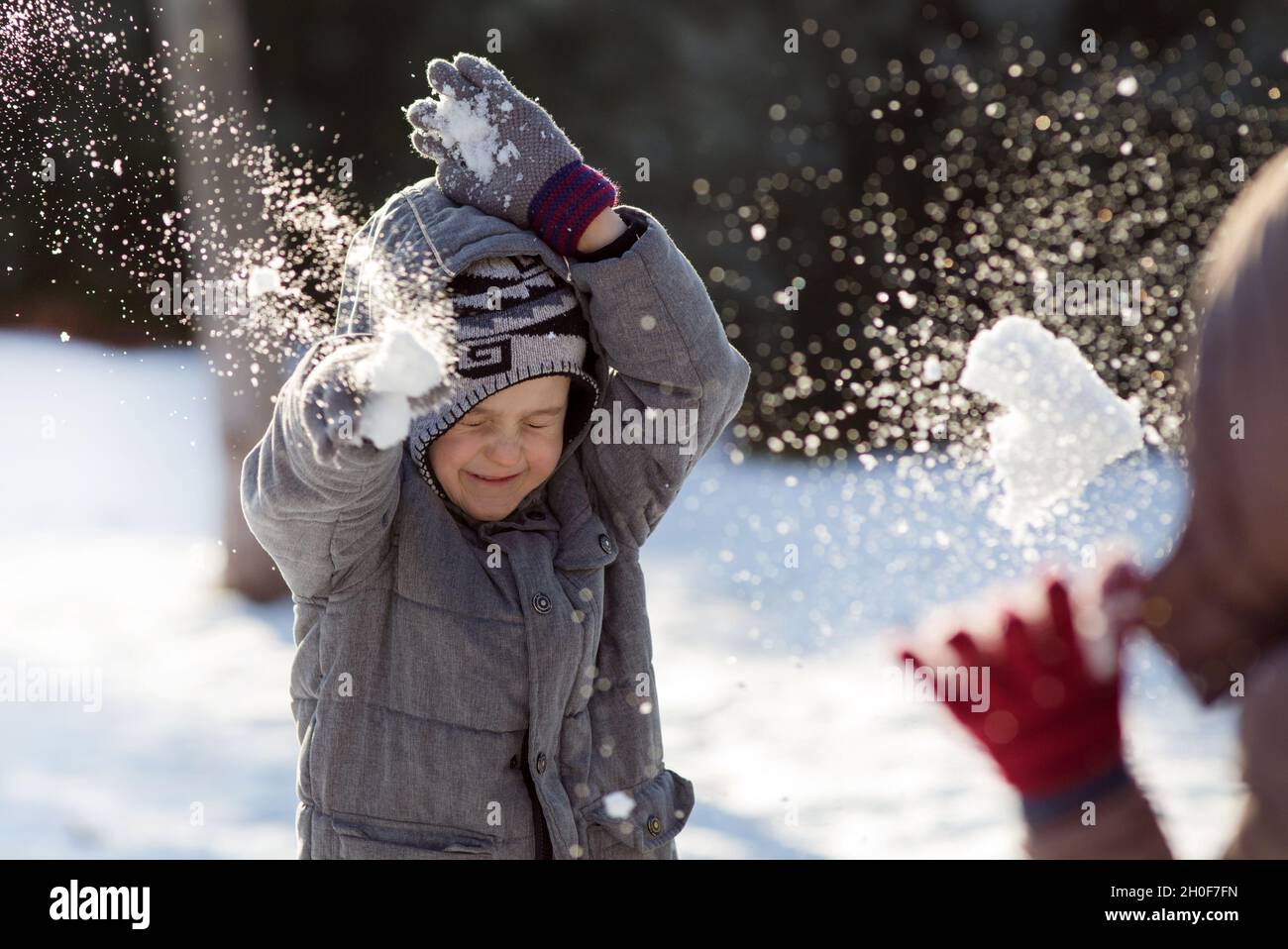 Boy and girl playing snowball fight on cold winter day in park Stock Photo