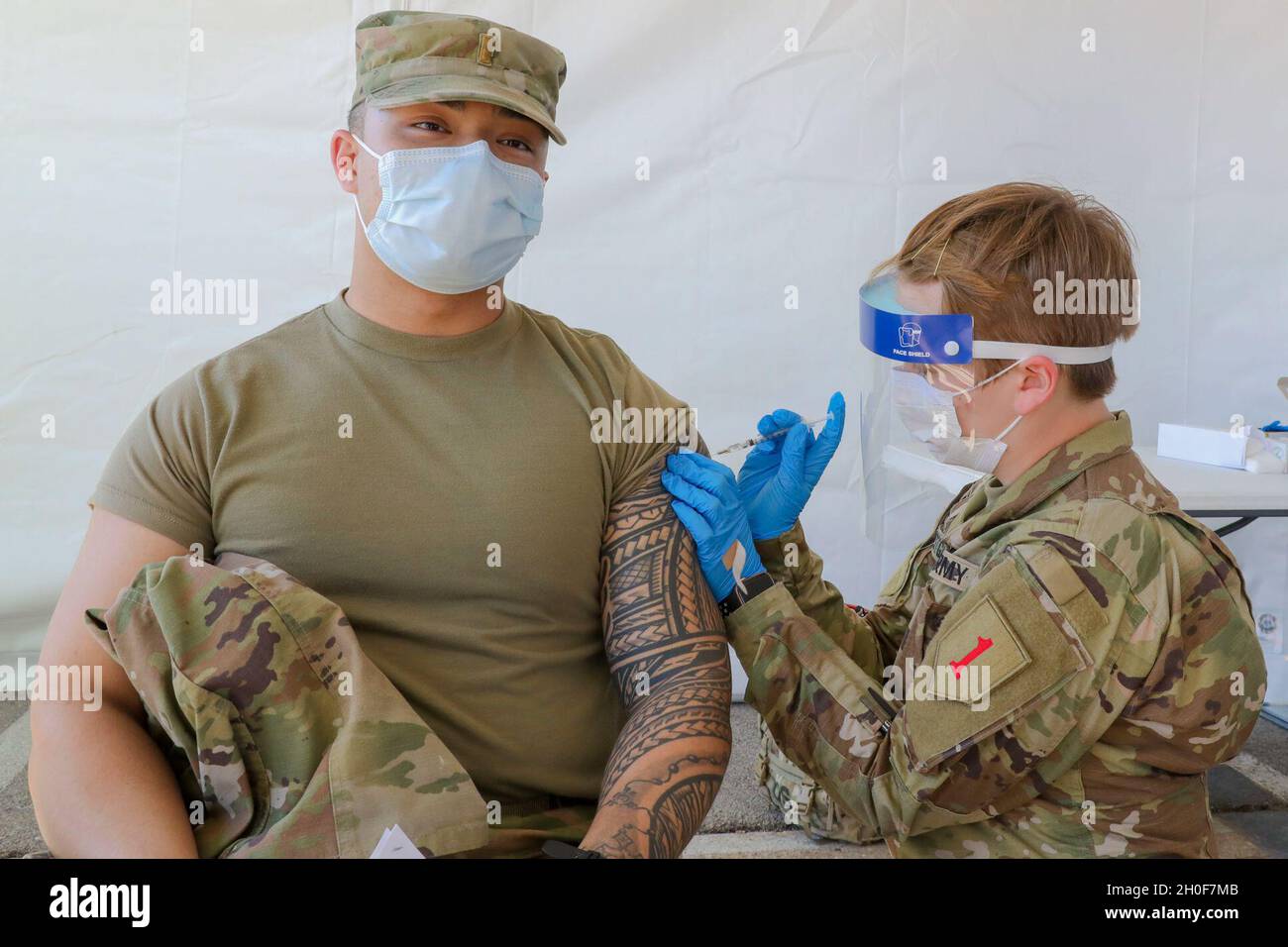 Spc. Zoe Festge, right, a combat medic assigned to 1st Battalion, 7th Field Artillery Regiment, 2nd Armored Brigade Combat Team, 1st Infantry Division, administers a dose of the COVID-19 vaccine to 2nd Lt. Joshua Ancheta, a medical-surgical nurse assigned to Madigan Army Medical Center at Joint Base Lewis-McChord, at the Fair Park COVID Community Vaccination Center in Dallas, on Feb. 23, 2021. U.S. Northern Command, through U.S. Army North, remains committed to providing continued, flexible Department of Defense support to the Federal Emergency Management Agency as part of the whole-of-governm Stock Photo