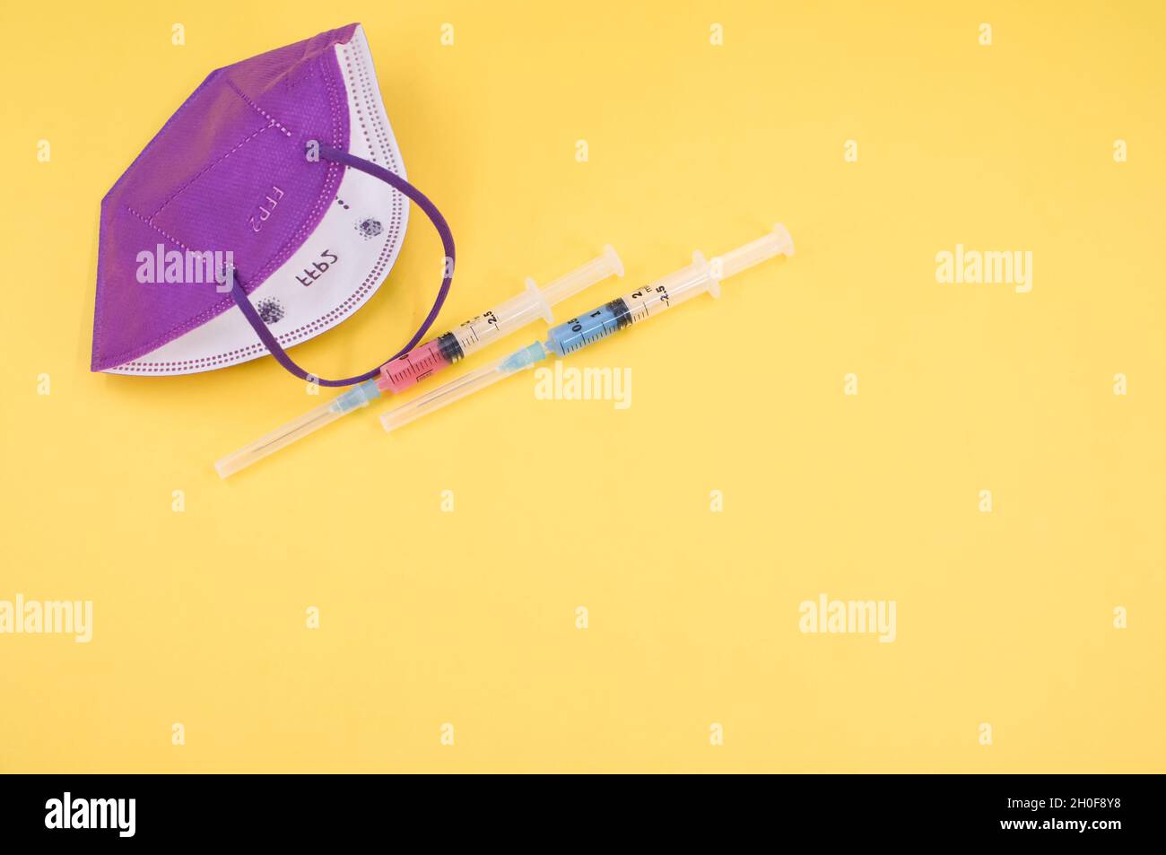 Isolated FFP2 respiratory mask and syringe on a yellow background Stock ...