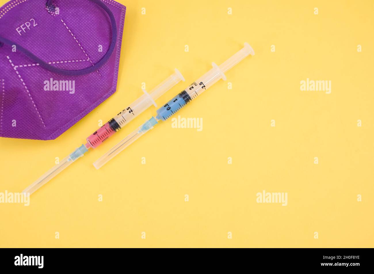Isolated FFP2 respiratory mask and syringe on a yellow background Stock ...