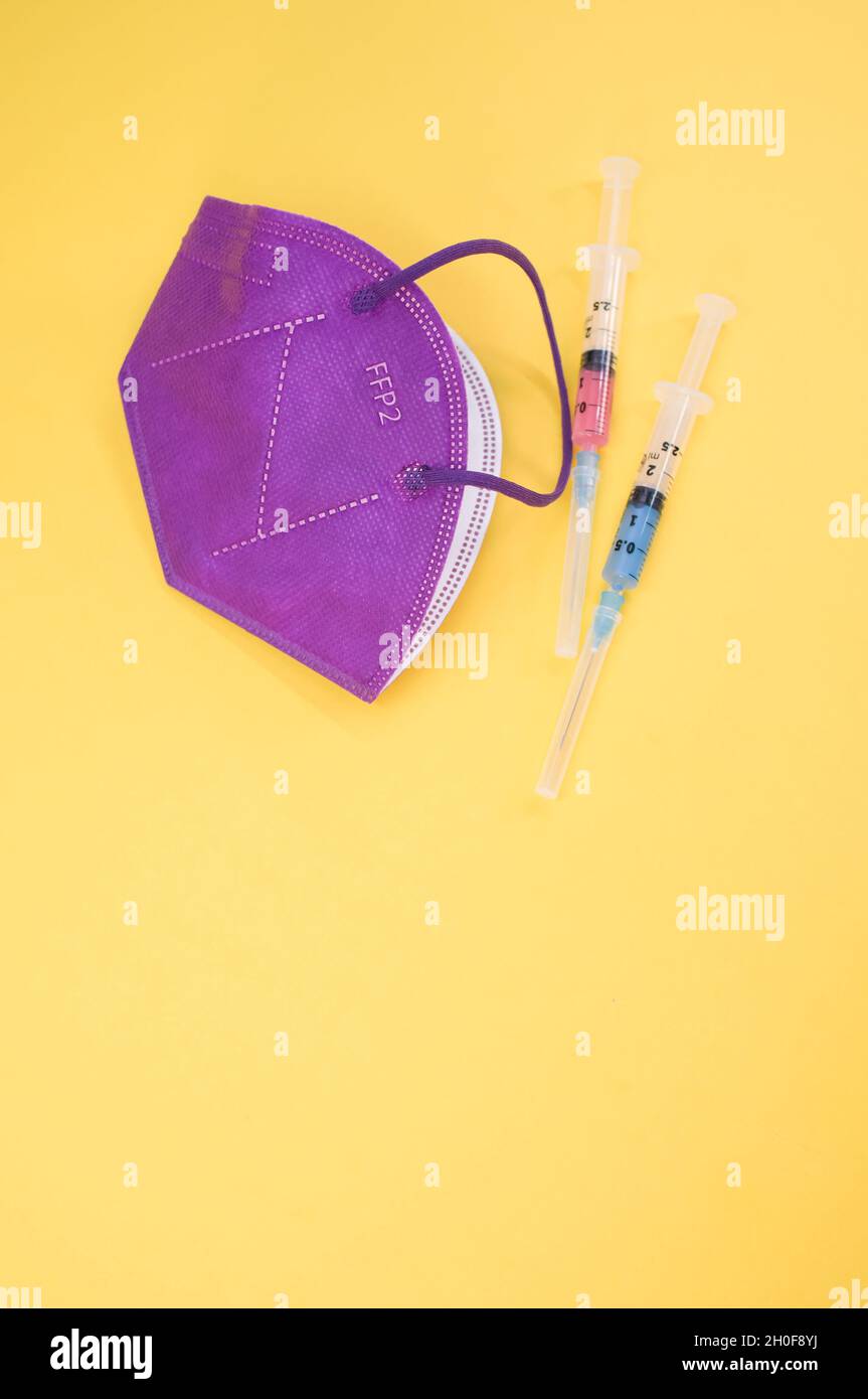 Isolated FFP2 respiratory mask and syringe on a yellow background Stock ...