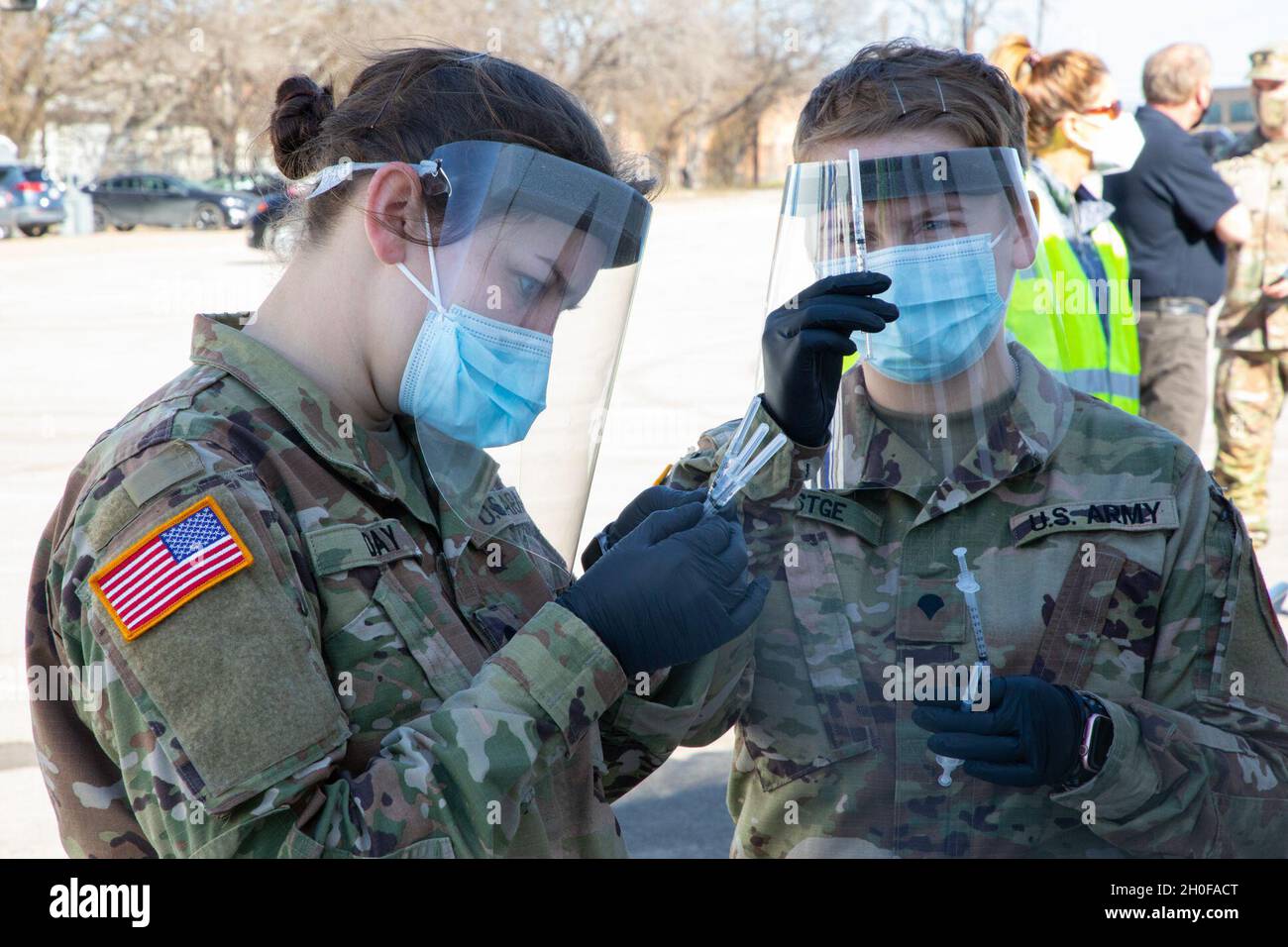 U.S. Army Spc. Haleigh Day (left) and Spc. Zoe Festge (right), 1st Battalion, 63rd Armored Regiment, 2nd Armor Brigade Combat Team, 1st Infantry Division, check the labels on the vaccine syringes at the Fair Park COVID-19 Community Vaccination Center in Dallas, Texas, Feb. 24, 2021. The Soldiers, deployed from Fort Riley, Kansas, support civilian medical personnel in administering COVID-19 vaccines. U.S. Northern Command, through U.S. Army North, remains committed to providing continued, flexible Department of Defense support to the Federal Emergency Management Agency as part of the whole-of-g Stock Photo