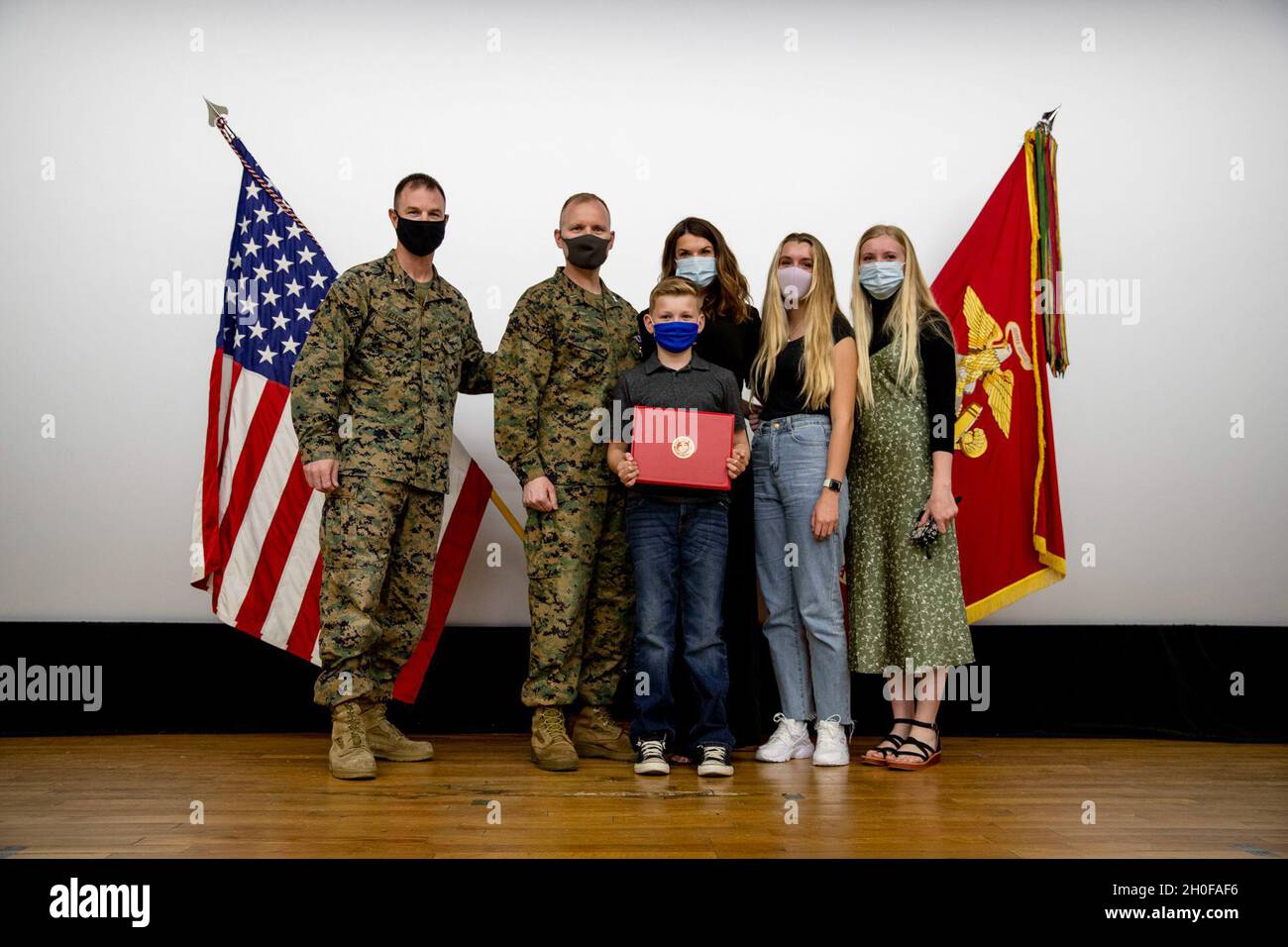 U.S. Marine Corps Brig. Gen. Kyle Ellison, Commanding General for 3rd Marine Expeditionary Brigade, poses for a photo with Capt. Kevin. W. Leishman, an Anti-Terrorism force protection officer, 3D MEB, and his family after a Purple Heart ceremony at the base theater, Camp Courtney, Okinawa, Japan, Feb. 24, 2021. During the ceremony Leishman was awarded for wounds sustained in action against enemies of the United States 16 years ago during the Battle of Fallujah, Operation Phantom Fury, Operation Iraqi Freedom. Stock Photo