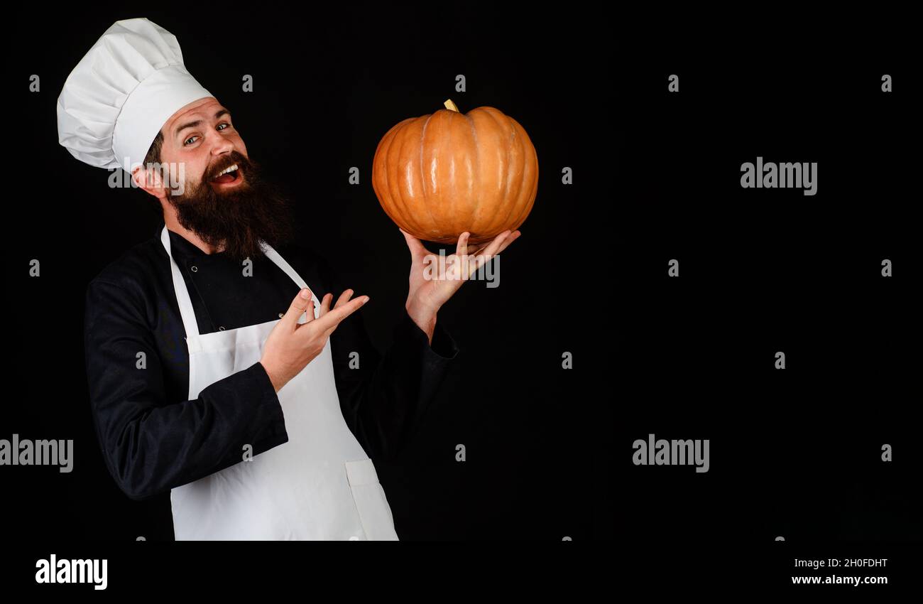 Chef man in white apron with pumpkin for culinary. Healthy organic harvest vegetables. Thanksgiving seasonal cooking ingredients. Copy space. Stock Photo