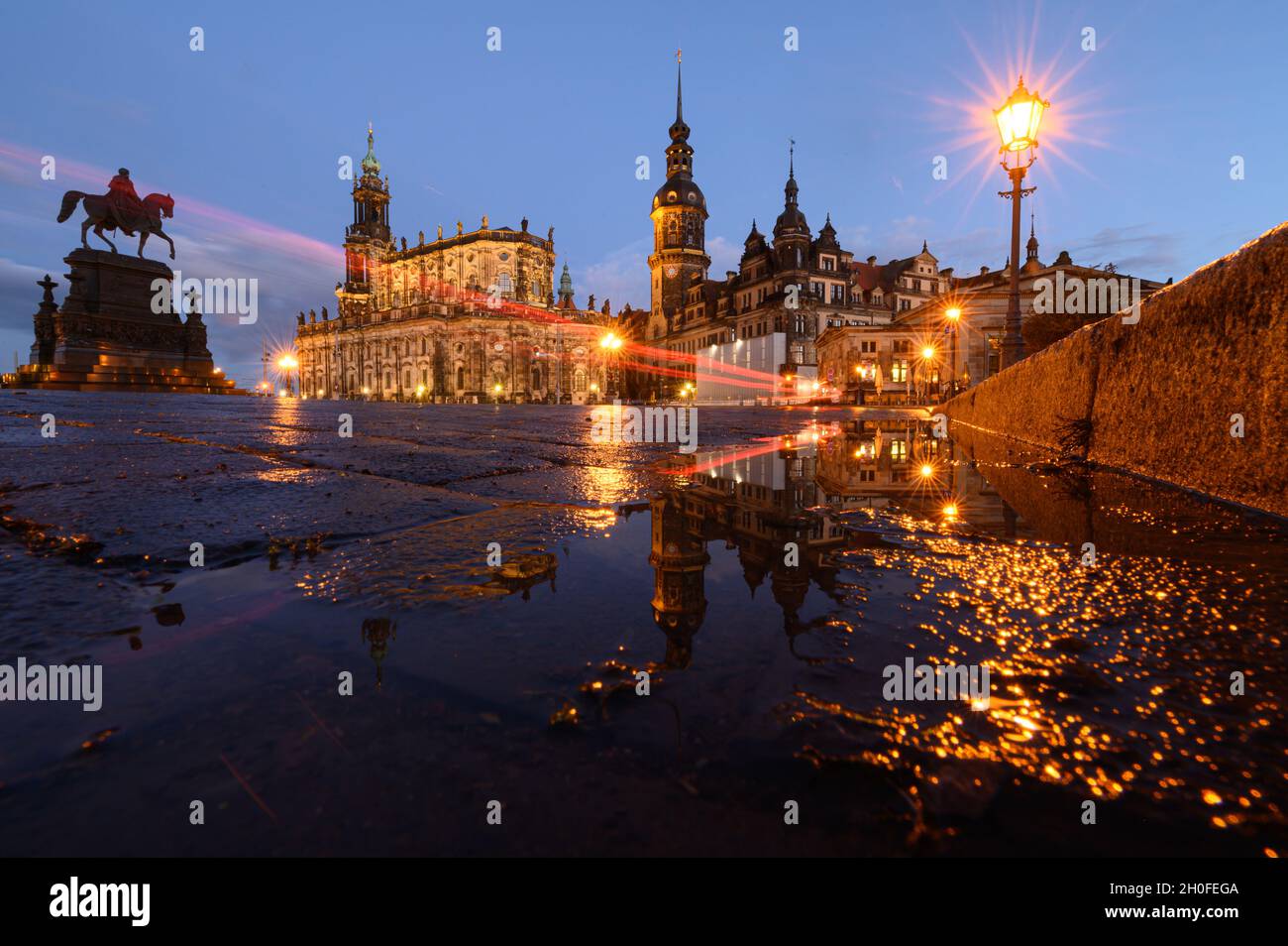 Dresden, Germany. 12th Oct, 2021. The equestrian statue of King Johann (l-r), the Hofkirche, the Hausmannsturm, the Residenzschloss and the Schinkelwache are reflected in a puddle on Theaterplatz in the evening after a rain shower. Credit: Robert Michael/dpa-Zentralbild/dpa/Alamy Live News Stock Photo