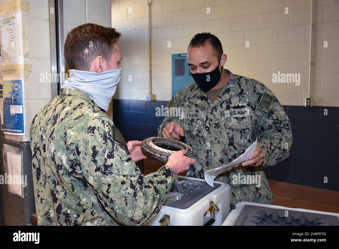 LS1 Antonio Evans (right) and LS2 Samuel Cahill (left) validate the part number and identifying information on a NRFI part with the information on a maintenance action form (MAF) prior to induction of the part to the local repair cycle. Stock Photo
