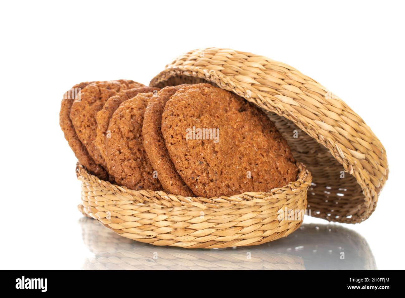 Several fresh oatmeal cookies with straw dishes, close-up, isolated on white. Stock Photo
