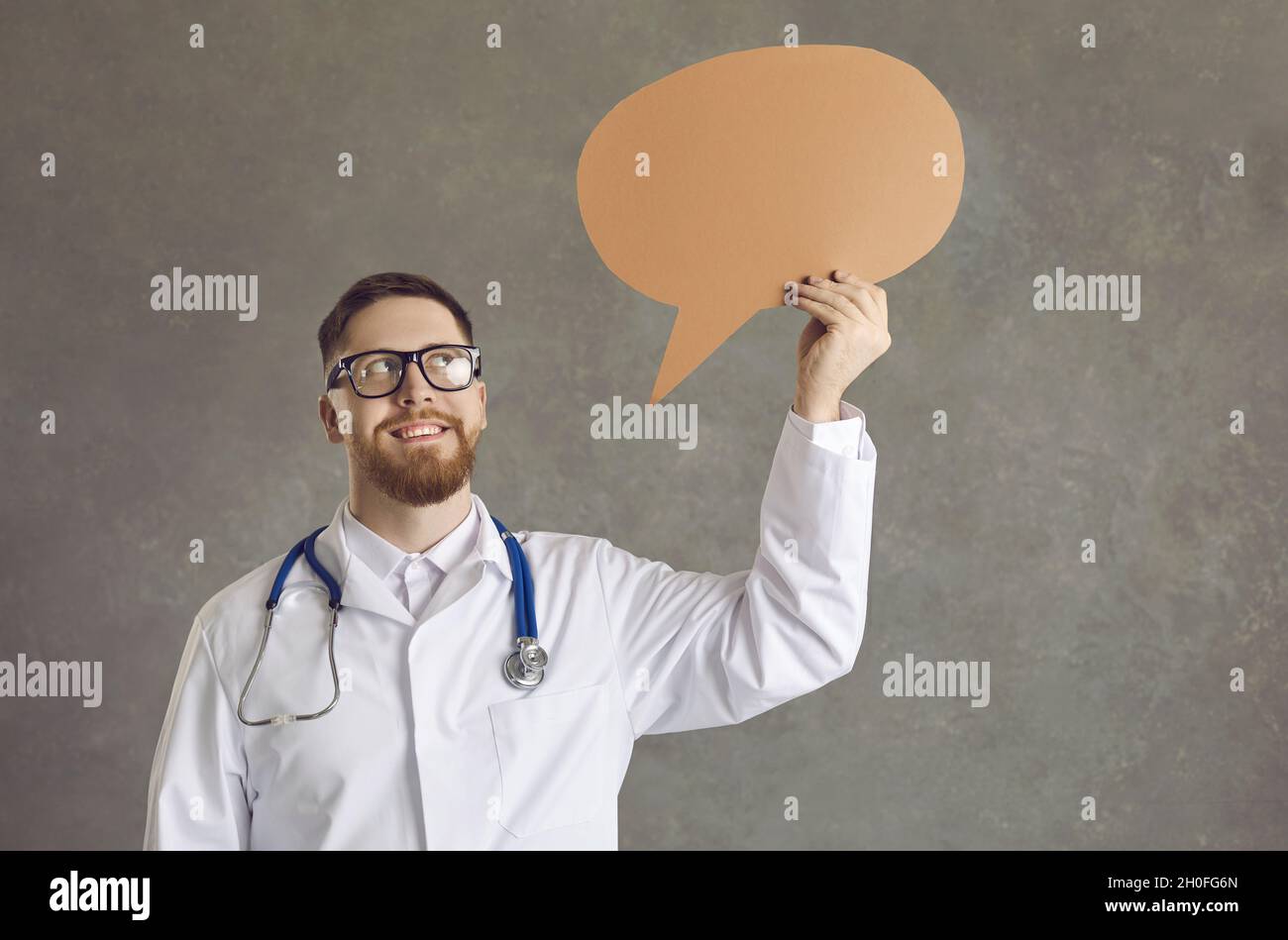 Happy young male nurse or doctor holding a blank speech balloon or thinking bubble Stock Photo