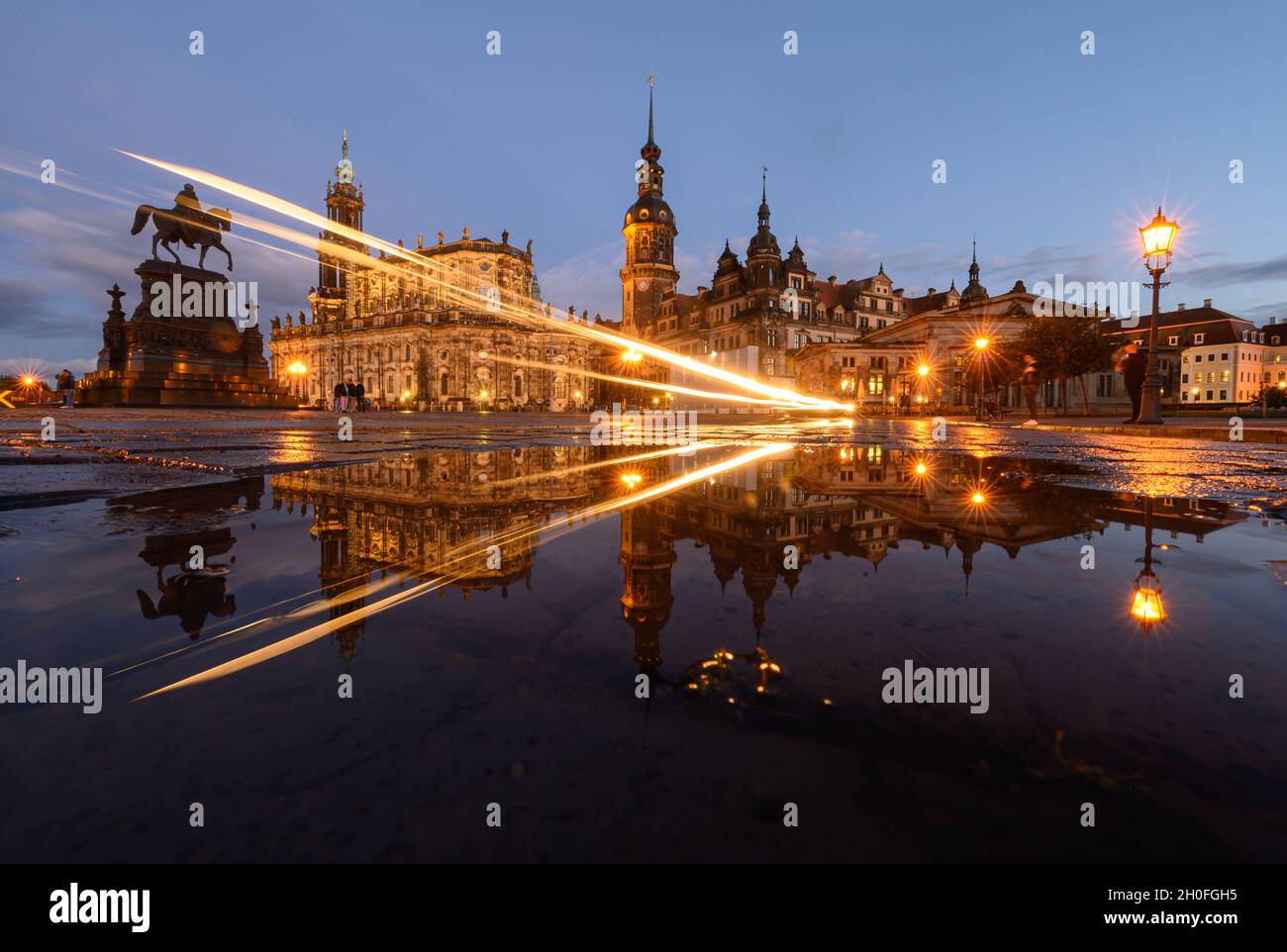 Dresden, Germany. 12th Oct, 2021. The equestrian statue of King Johann (l-r), the Hofkirche, the Hausmannsturm, the Residenzschloss and the Schinkelwache are reflected in a puddle on Theaterplatz in the evening after a rain shower. Credit: Robert Michael/dpa-Zentralbild/dpa/Alamy Live News Stock Photo