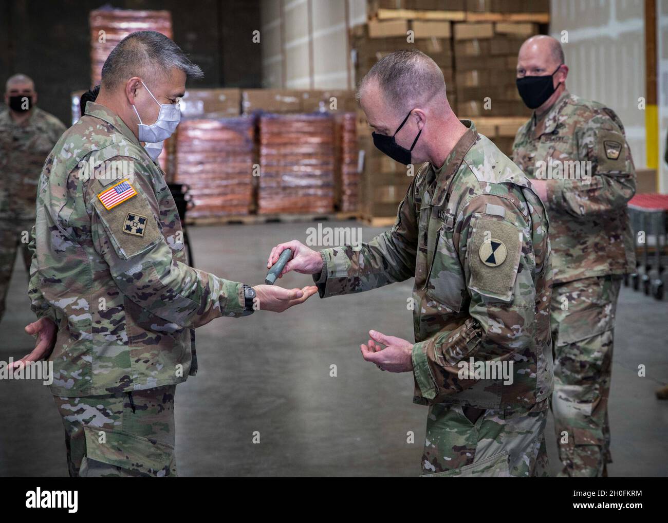 Command Sgt. Maj. Kelly Wickel provides hand sanitizer to Staff Sgt. Alan Dequilla after presenting Dequilla’s award for outstanding service during food bank operations in Kent, Washington, Feb. 26, 2021. Northwest Harvest ended their request for National Guard support so JTF Steelhead can shift efforts towards COVID-19 vaccine administration. The Washington National Guard has supported Northwest Harvest in food packaging since April, 2020 and has aided in the distribution of over 7.8 million pounds of food at various Northwest Harvest sites across Washington. Stock Photo