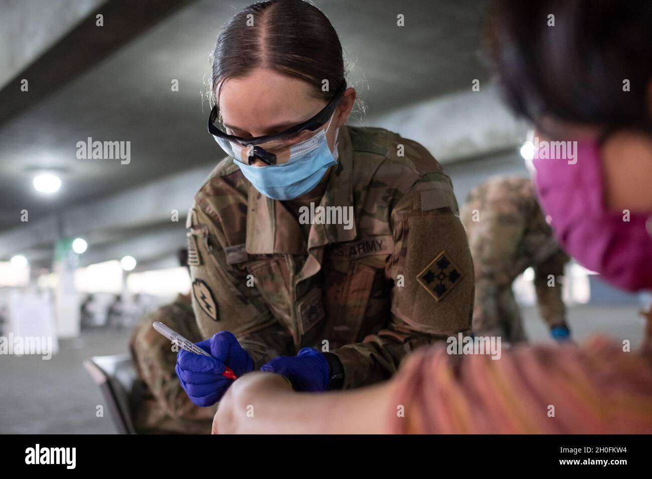 U.S. Army Staff Sgt. Kirsten Pavao of La Habra, Calif., a combat medic assigned to Headquarters and Headquarters Battery, 2nd Battalion, 12th Field Artillery Regiment, 1st Stryker Brigade Combat Team, 4th Infantry Division, administers the COVID vaccine at the California State University Los Angeles Community Vaccination Center, Feb. 26, 2021. Pavao vaccinated people at the CVC at Cal State LA. U.S. Northern Command, through U.S. Army North, remains committed to providing continued, flexible Department of Defense support to the Federal Emergency Management Agency as part of the whole-of-govern Stock Photo