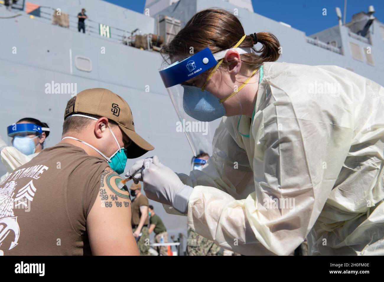 210226-N-FO865-3063     MANAMA, Bahrain (Feb. 26, 2021) – Lt. Emily Goodwin, right, a doctor assigned to Navy Medicine Readiness and Training Unit Bahrain, administers the COVID-19 vaccine to Personnel Specialist 2nd Class Arnold McQuade, assigned to amphibious transport dock ship USS San Diego (LPD 22), in Manama, Bahrain, Feb. 26. San Diego, part of the Makin Island Amphibious Ready Group, and the 15th Marine Expeditionary Unit are deployed to the U.S. 5th Fleet area of operations in support of naval operations to ensure maritime stability and security in the Central Region, connecting the M Stock Photo