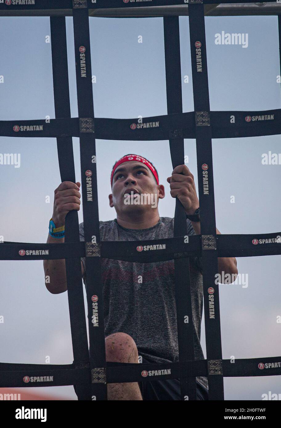 A contestant participating in the Okinawa Spartan Race scales a rope