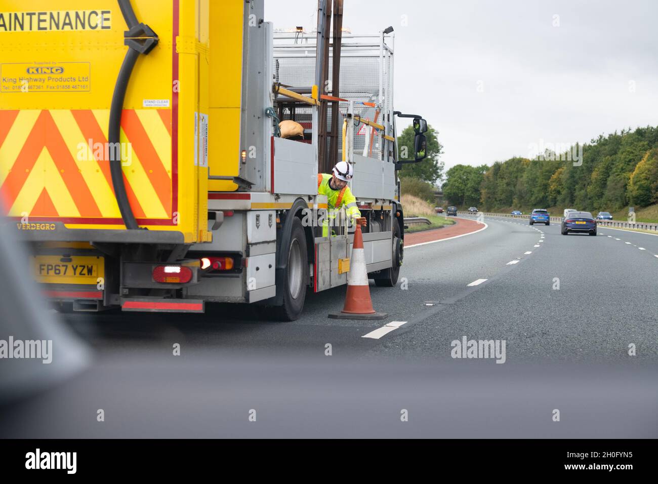 worker collecting traffic cones manually by hand on UK motorway Stock Photo