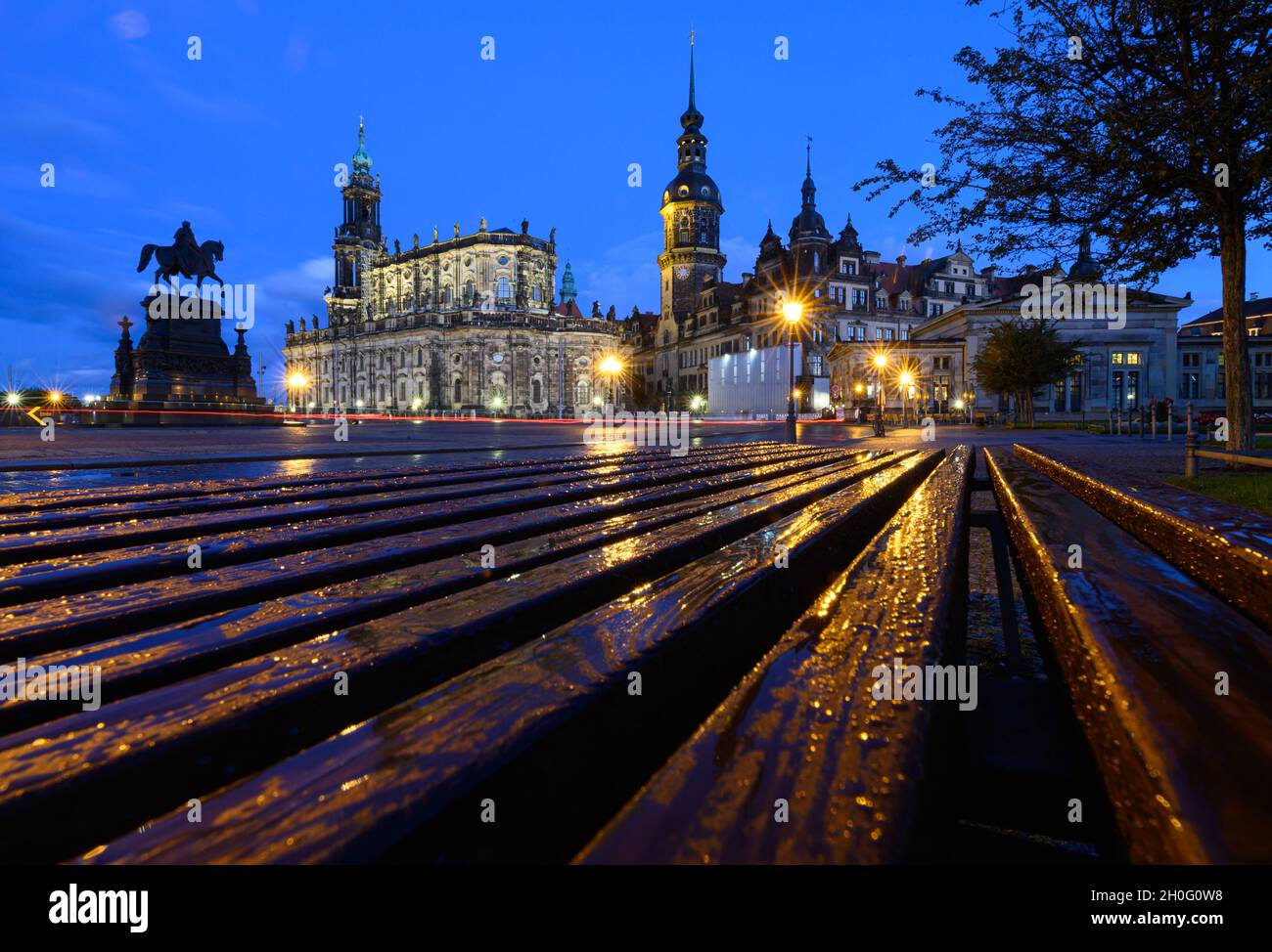 Dresden, Germany. 12th Oct, 2021. A bench on the Theaterplatz with the equestrian statue of King Johann (l-r), the Hofkirche, the Hausmannsturm, the Residenzschloss and the Schinkelwache is wet with raindrops in the evening after a shower. Credit: Robert Michael/dpa-Zentralbild/dpa/Alamy Live News Stock Photo