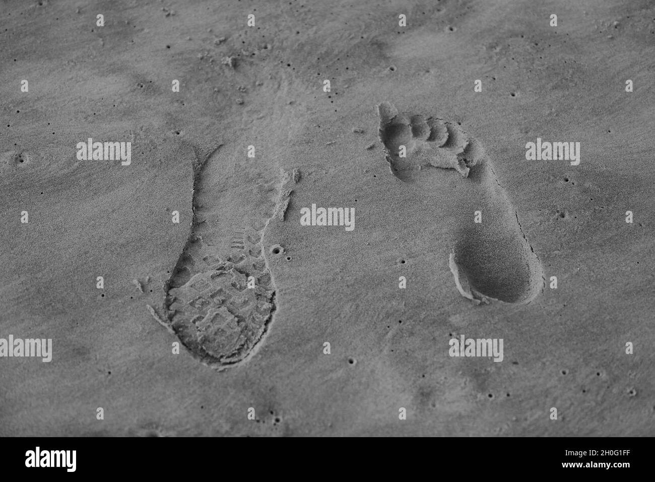 Two feet, one bare & one in shoes, going in opposite directions, close-up on beach sand. Stock Photo