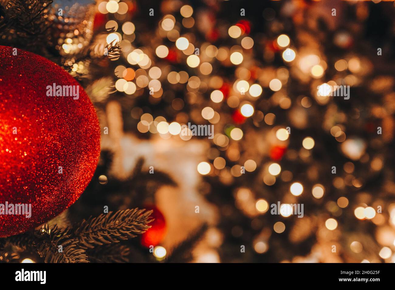 Christmas Toy Red Ball Hanging On The Christmas Tree With Blurry Golden Festive Bokeh Lights On Background. Merry Christmas And Happy New Year 2022 Ma Stock Photo - Alamy
