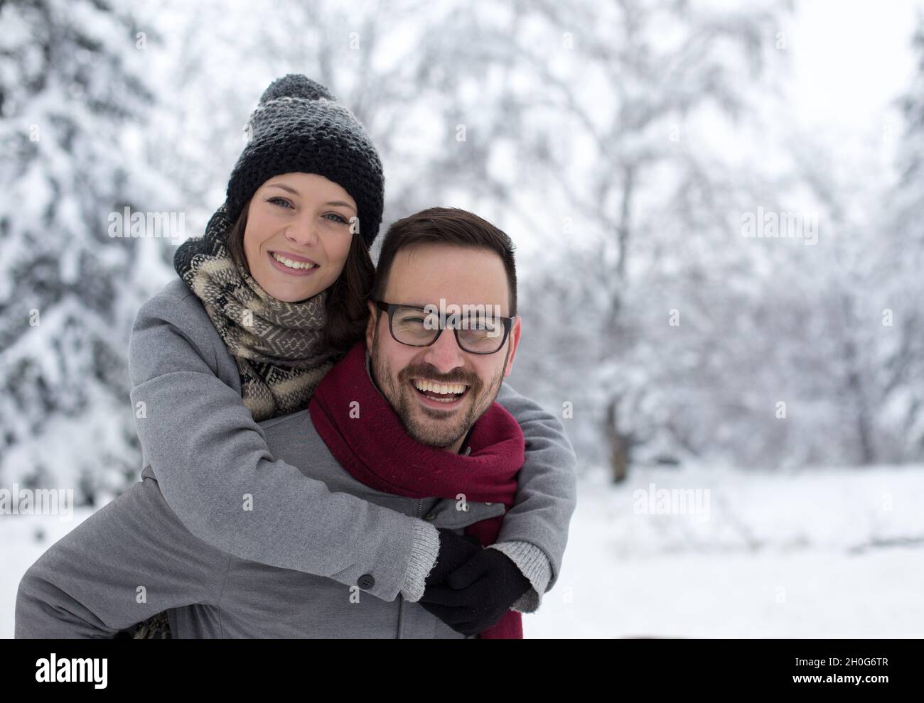 Portrait of happy young couple hugging on snow in forest Stock Photo ...