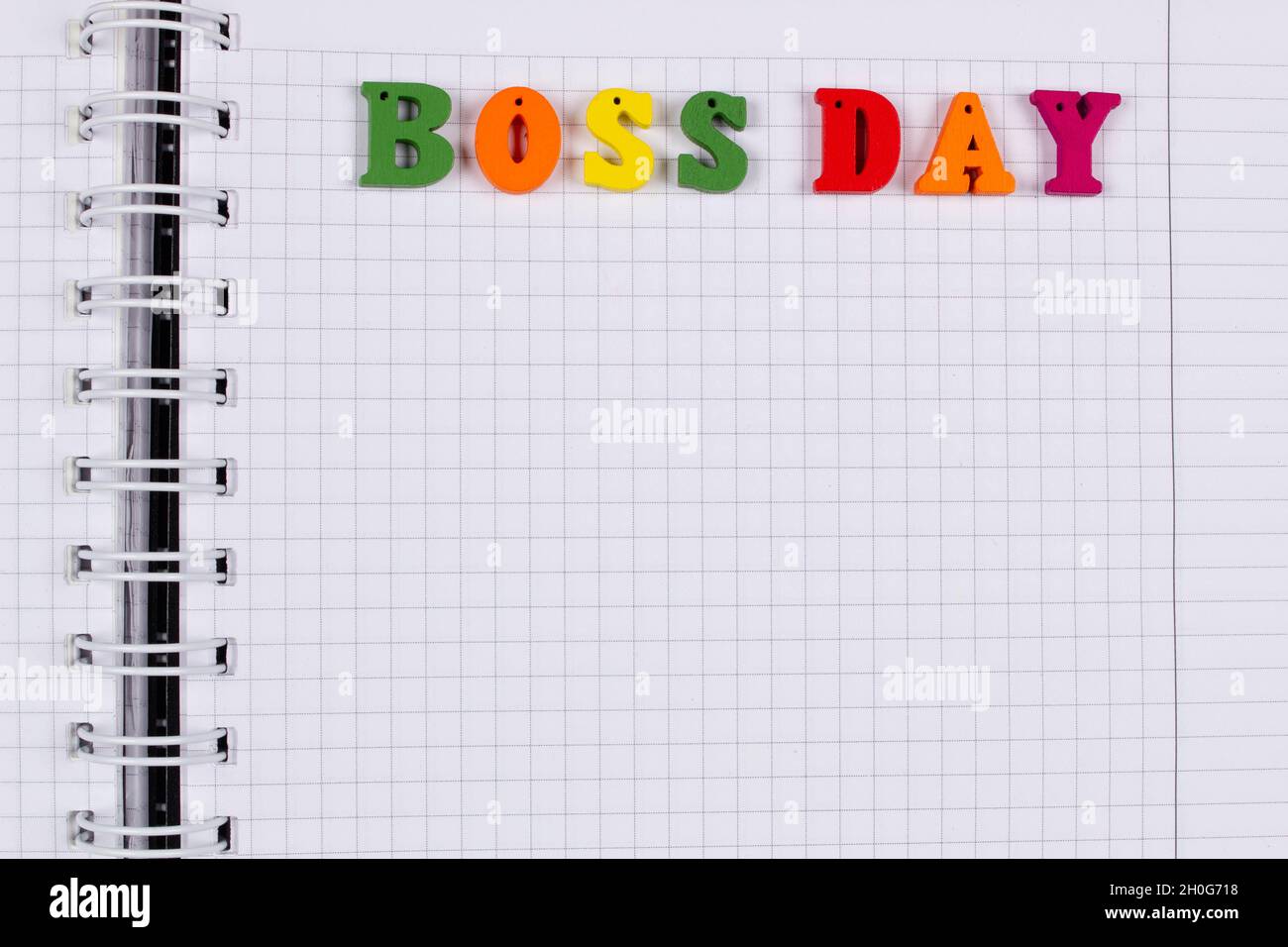 National Happy Boss Day. Multicolored colorful letters in a squared exercise book on the table. Bosses Day office greeting card with copy space for te Stock Photo