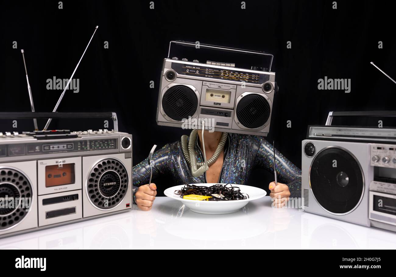 Woman with ghettoblaster as a head eating cassette tape Stock Photo