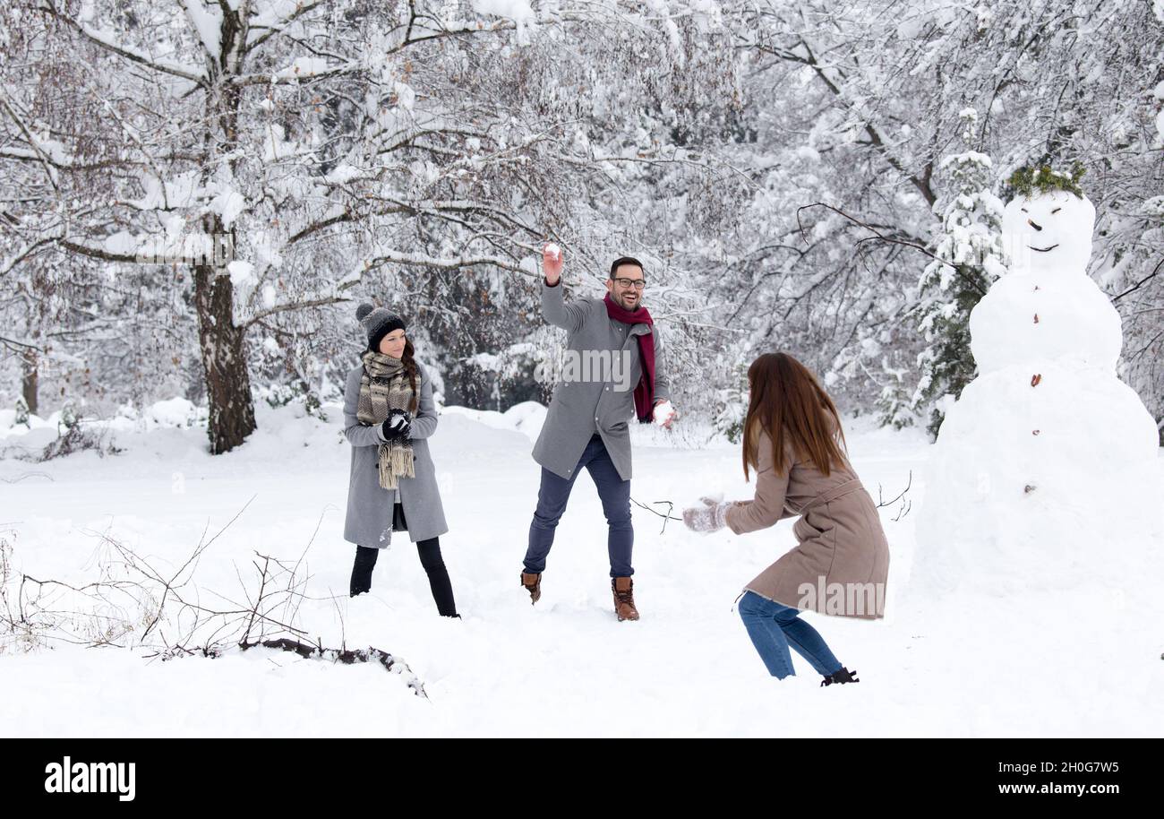 Friends having fun on snow in park, playing snowball fight Stock Photo ...