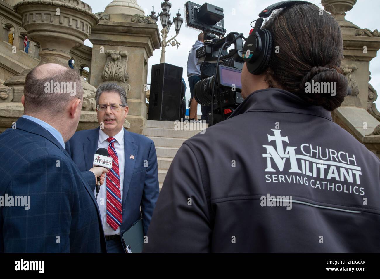 Lansing, Michigan, USA. 12th Oct, 2021. A TV crew from the conservative Catholic Church Militant interviews Matt DePerno, a Trump-endorsed candidate for Michigan Attorney-General. DePerno was speaking at a rally at the Michigan State Capitol demanding a 'forensic audit' of the 2020 presidential election results. Former President Trump charges that voter fraud was the reason he lost the election in Michigan by more than 150,000 votes. Credit: Jim West/Alamy Live News Stock Photo