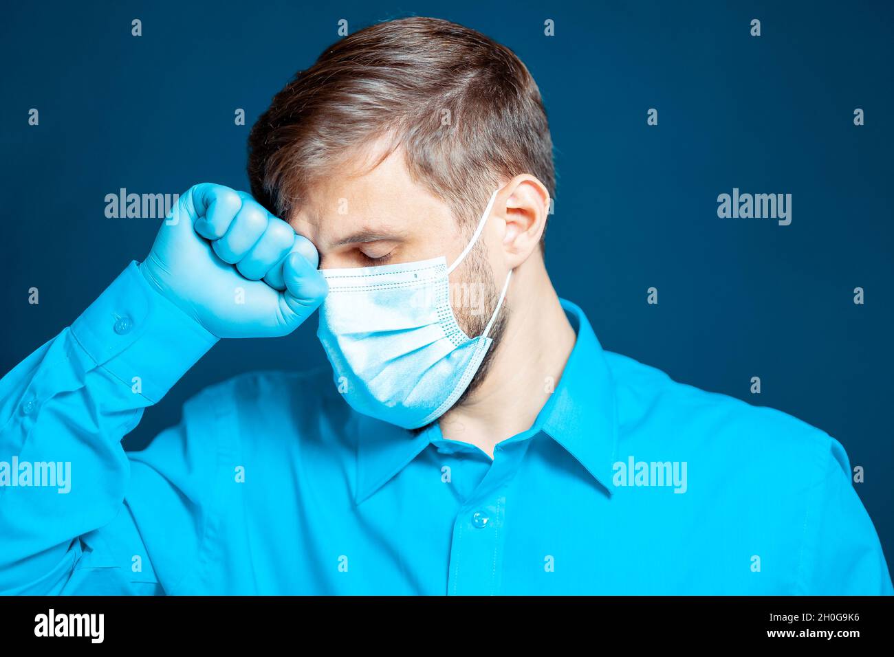 A doctor in a medical mask and gloves, in a blue uniform, leaned his ...