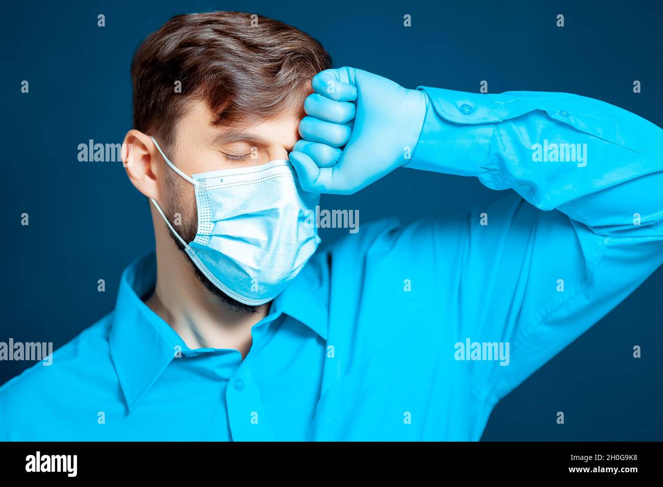 A doctor in a medical mask and gloves, in a blue uniform, leaned his ...