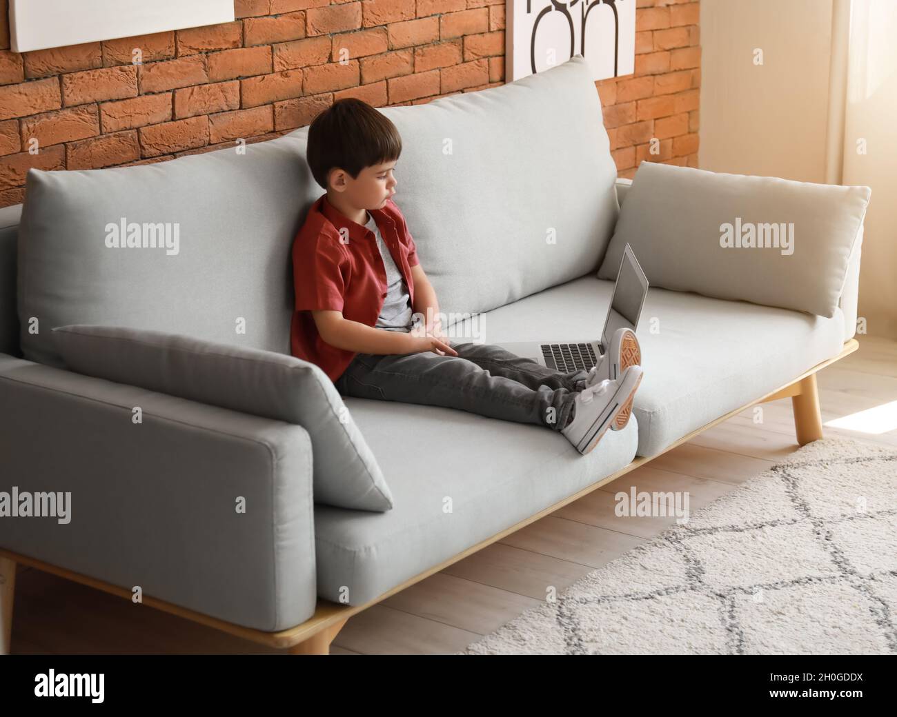 Little boy watching cartoons with laptop on sofa at home Stock Photo ...
