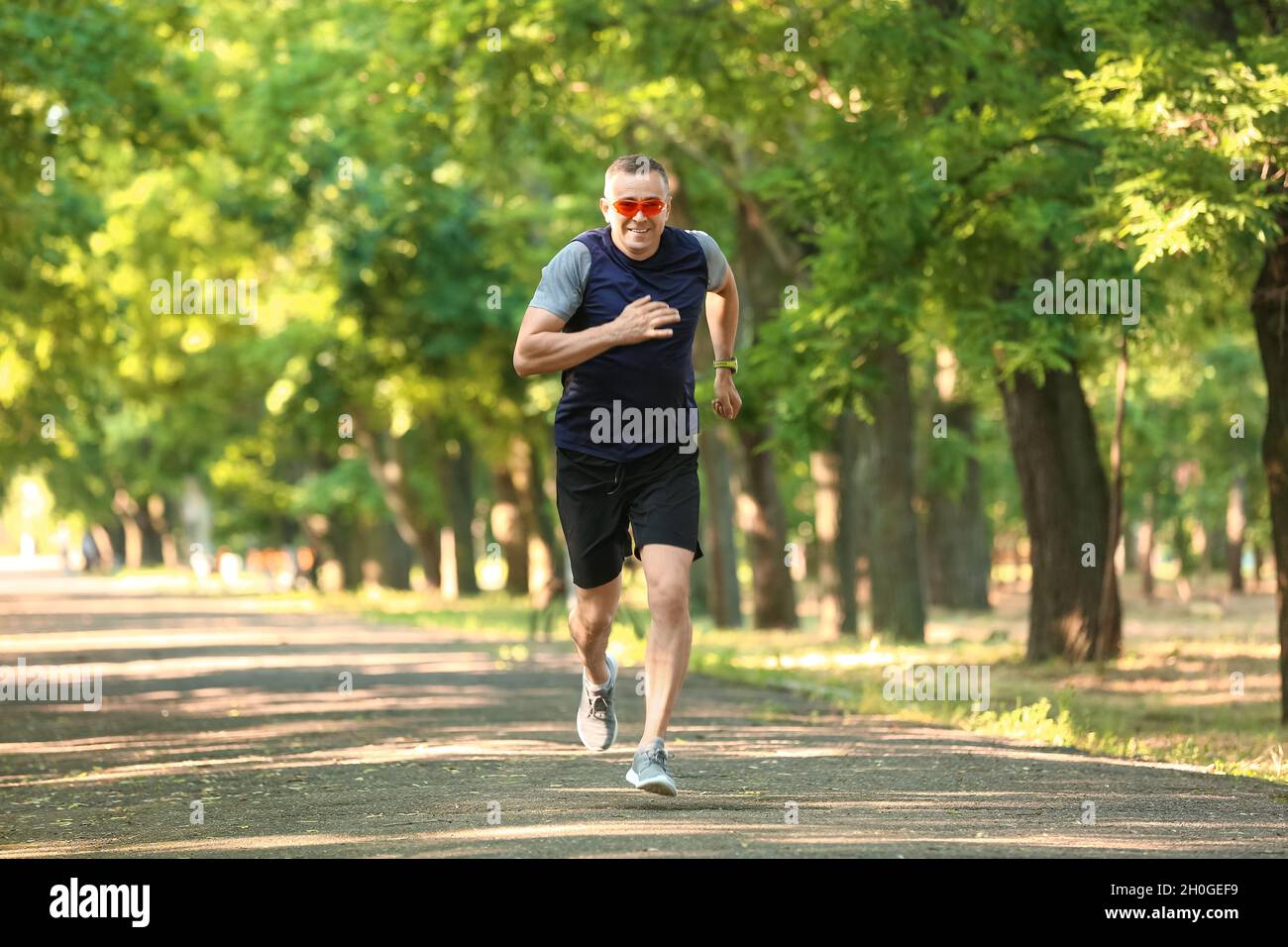 Sporty mature man with eyeglasses running in park Stock Photo - Alamy