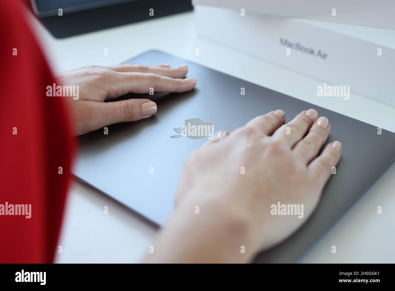 Minsk, Belarus, October 11, 2021: Woman hand rests on top cover of Apple Macbook Air Stock Photo