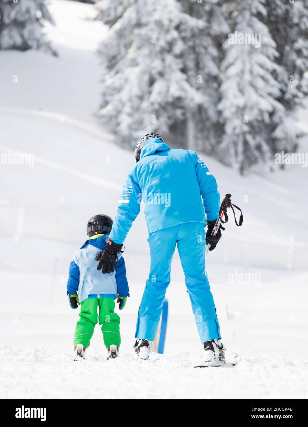 Rear view of young boy learning skiing with teacher on mountains Stock ...