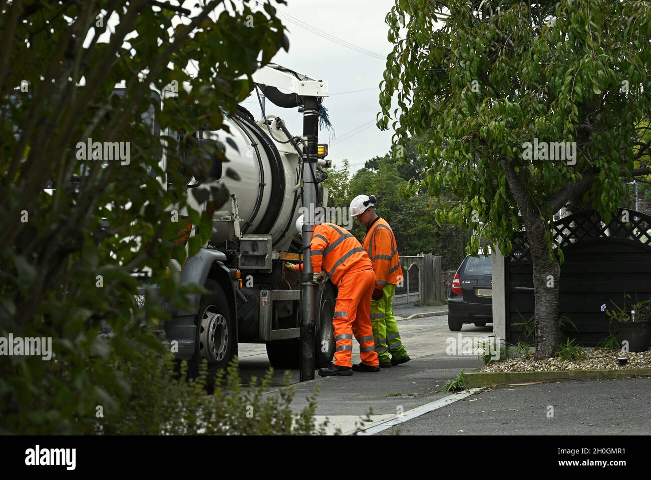 Highway Maintenance. These men are clearing a kerbside drain in a residential street to ensure the road is clear of surface water at Wickford, Essex. Stock Photo