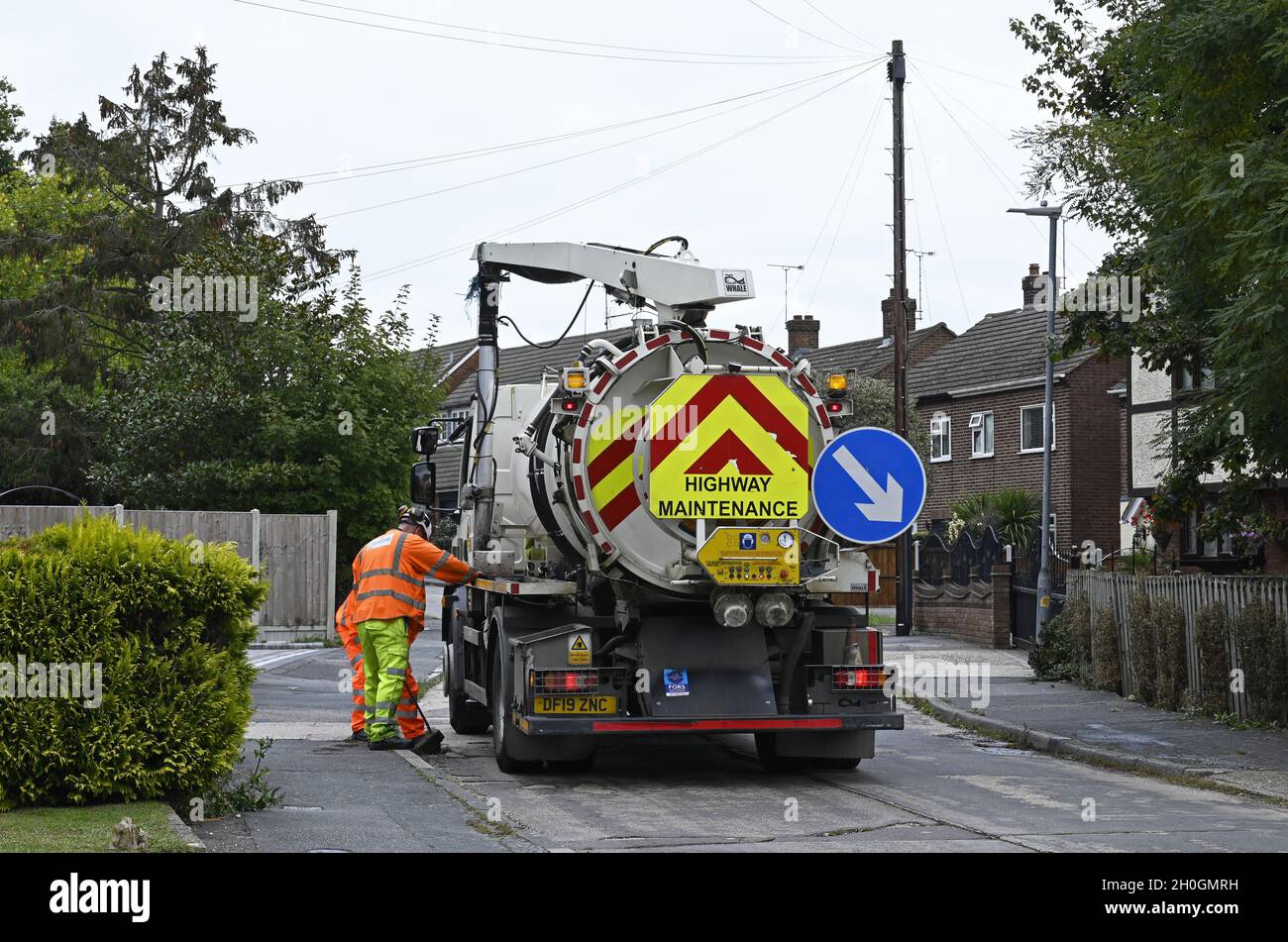 Highway Maintenance. These men are clearing a kerbside drain in a residential street to ensure the road is clear of surface water at Wickford, Essex. Stock Photo
