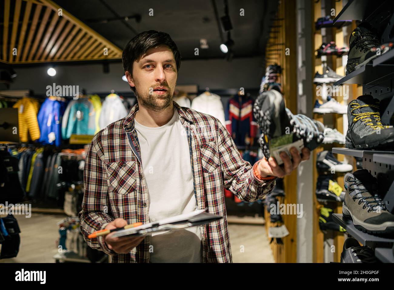 Store clerk helping customer try hiking boots at outdoors equipment shop. Salesman demonstrating trekking and hiking footwear for outdoor trails. Cons Stock Photo Alamy