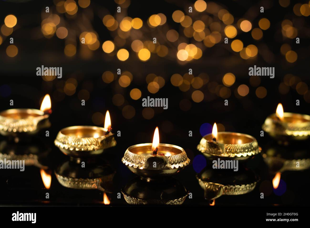 Golden Brass Diya Illuminated With Reflection In Dark Black Background With Bokeh Effect. Indian Festival Theme For Diwali Pooja, Navratri, Dussehra P Stock Photo