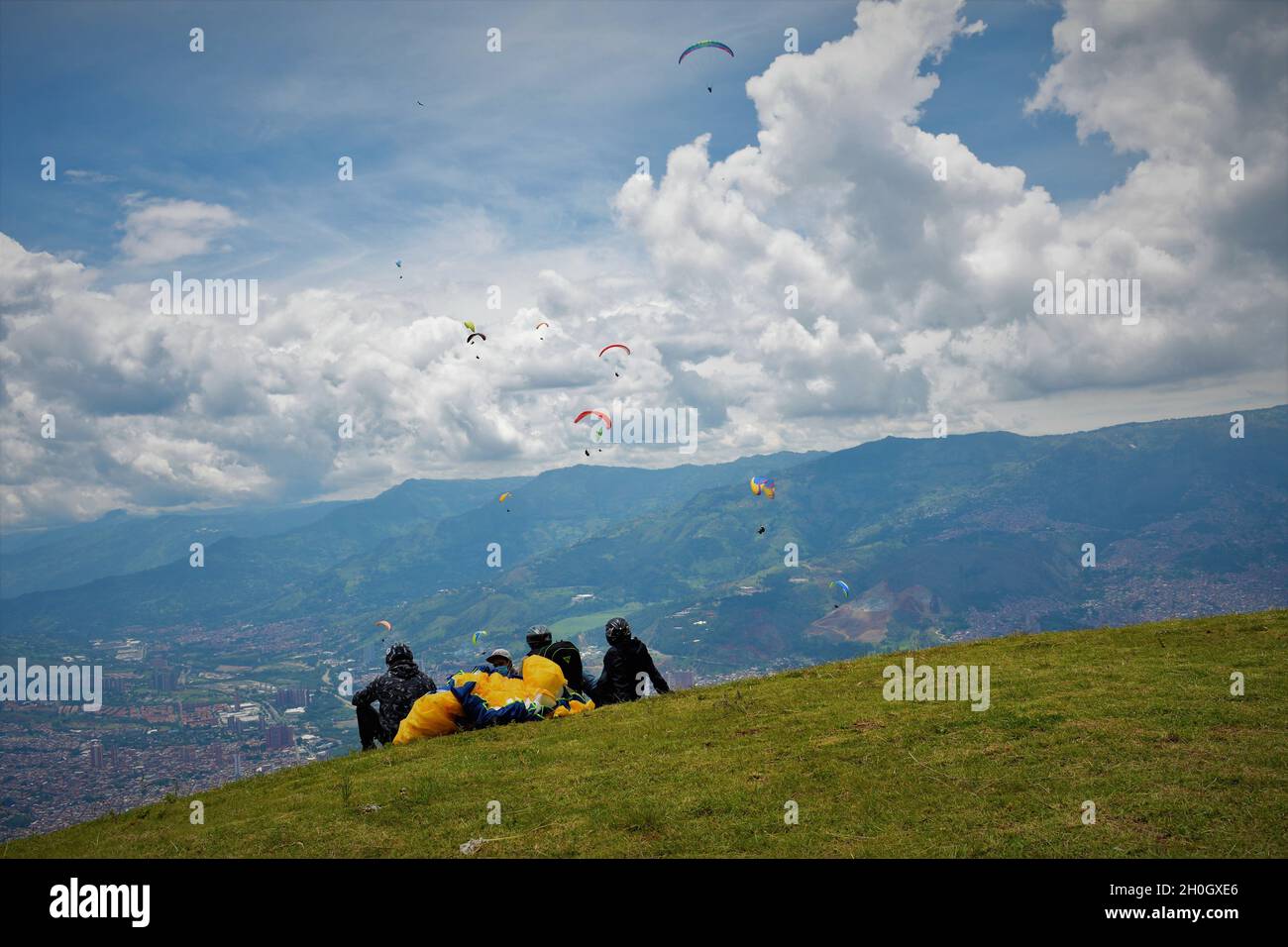 People sitting on the hill and looking at Medellin Paragliding in San Felix, Colombia Stock Photo
