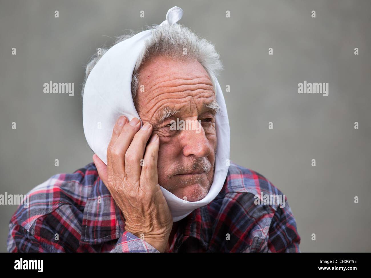 Old man having toothache, binding head with cold cloth Stock Photo