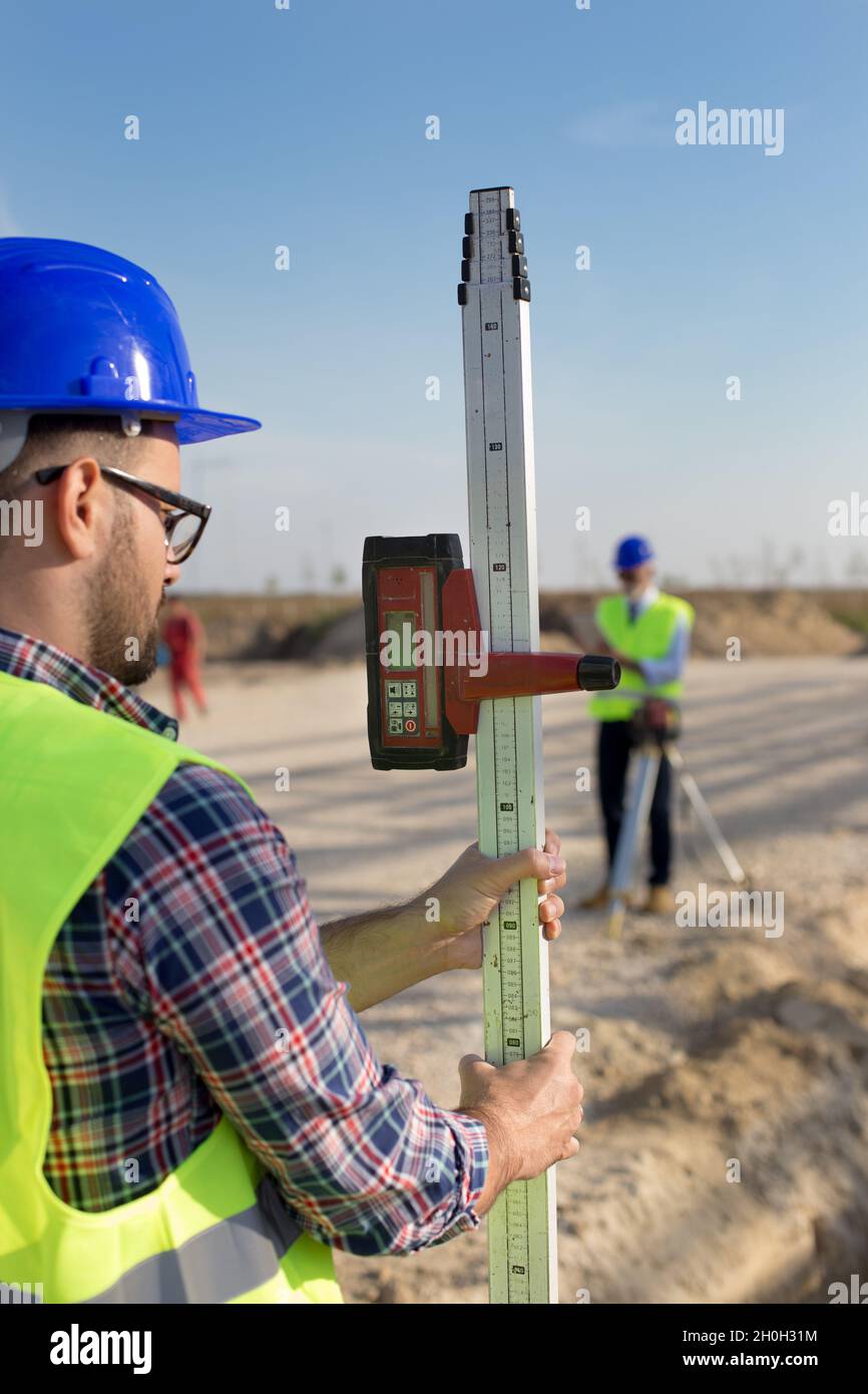 Construction worker holding laser measuring tool on building site Stock
