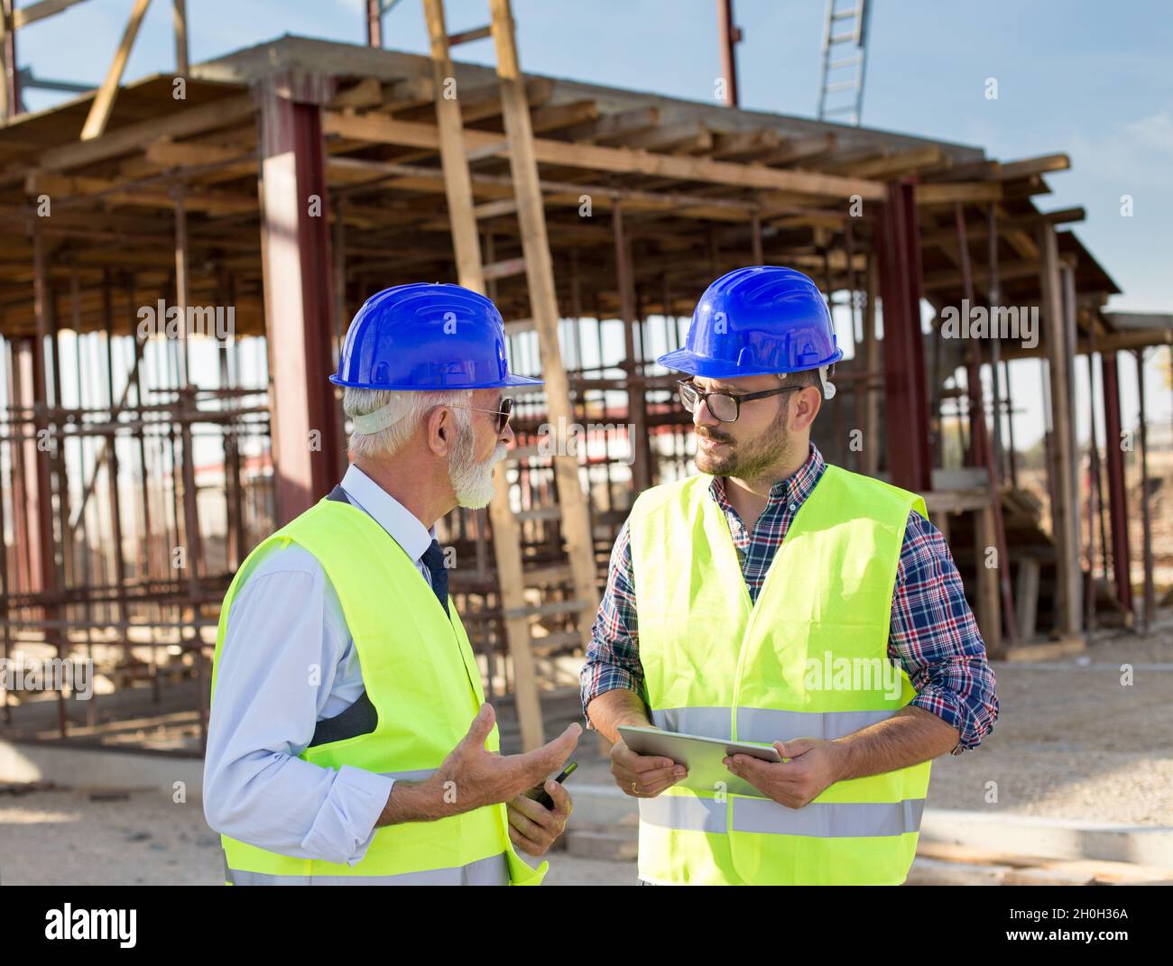 Two satisfied engineers with tablet talking at building site Stock Photo