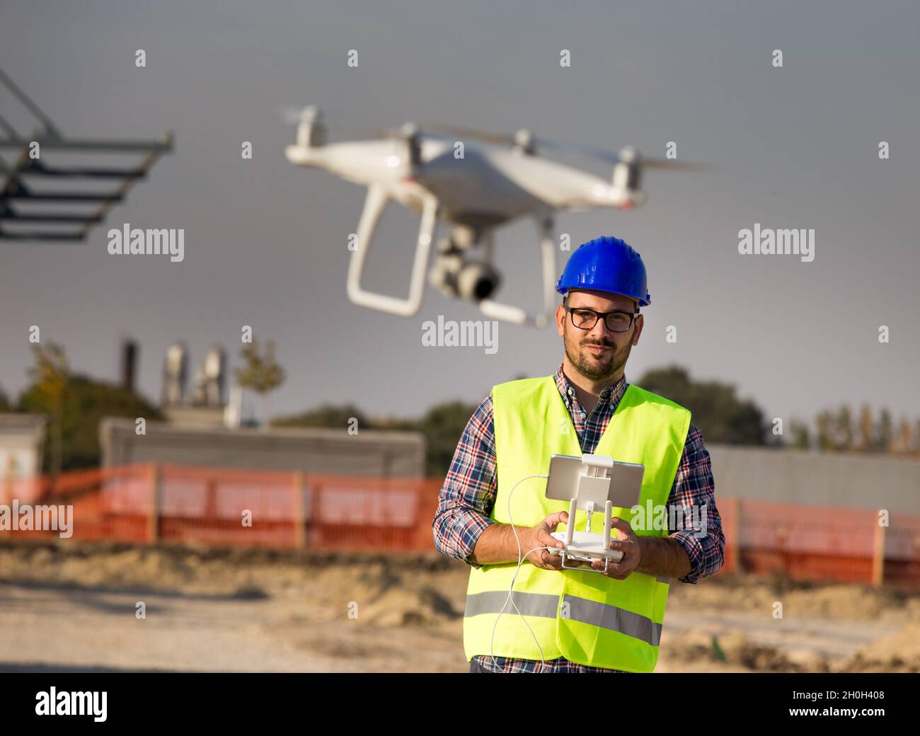 Portrait of engineer with helmet operating with drone on remote control