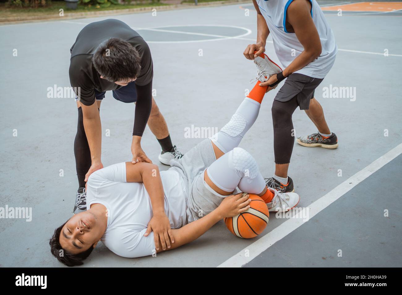 a basketball player is lying on the floor due to a leg injury being