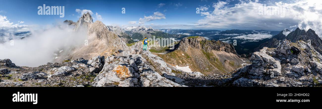 Alpine panorama, hiker on a summit, Westliche Toerlspitze, mountains in dramatic clouds, on the left Patenkirchner Dreitorspitze and Zugspitze Stock Photo