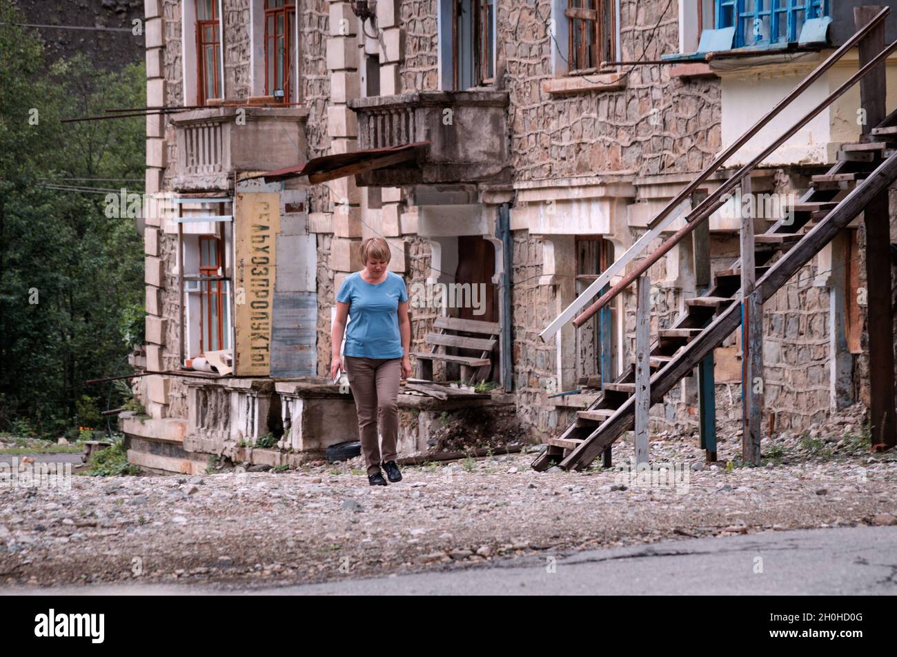 SADON, RUSSIA - 07 25 2021: Lonely stranger hesitating to step further on desolated territory beside old abandoned partially collapsed building with Stock Photo